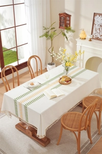 Detail of waterproof checkered tablecloth with embroidered flowers and beige tassels