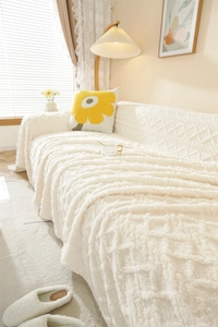 Detail of plush white sofa cover with textured diamond pattern in a cozy home setting