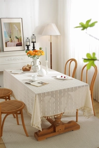 Close-up of beige hollow lace tablecloth featuring geometric crochet and cotton tassels
