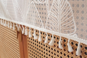 Close-up of white lace table runner featuring floral jacquard patterns and elegant tassels