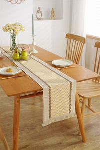 Detail of cotton linen table runner with yellow diamond pattern and fringed tassels