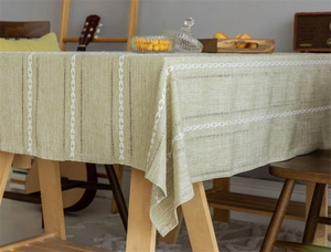 Detail of light green tablecloth with white leaf embroidery and hollow stripes