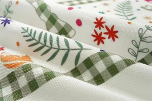 Close-up of Easter polyester fabric with green plaid, red flowers, and leafy patterns