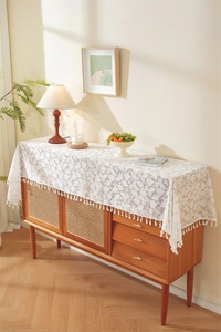 Detailed close-up of white lace table runner with leaf patterns and elegant fringe trim