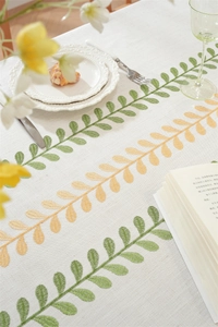 Detailed close-up of embroidered leaf pattern and texture on beige linen tablecloth