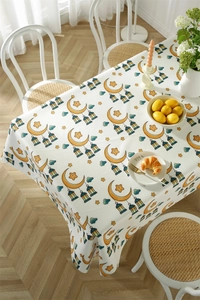 Close-up of Eid Mubarak tablecloth featuring golden moon and star patterns on wood table