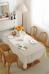 Detailed texture of beige hollow-out lace tablecloth with elegant tassel edges on table