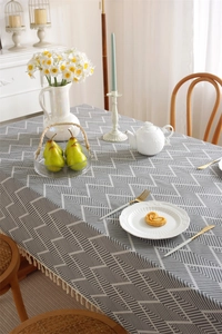 Detail of gray geometric herringbone tablecloth with decorative cream cotton tassels