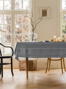 Detailed close-up of grey-blue textured tablecloth with triple white decorative stitching