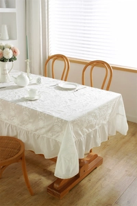 Detail of French blue and white floral embroidery on white cotton ruffled tablecloth