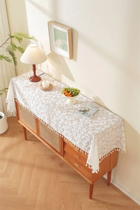 Detail of white lace table runner with 3D floral embroidery and elegant hanging tassels