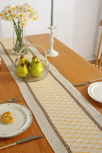 Close-up of woven cotton table runner with yellow diamond pattern and brown trim detail