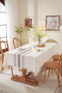 Detailed embroidery of coffee-colored leaves and handmade tassels on beige linen tablecloth