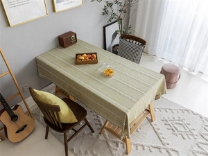 Close-up detail of green polyester jacquard tablecloth with white wavy lines and fringe