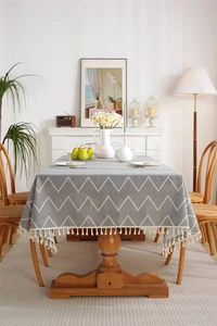 Close-up of bohemian grey tablecloth with white geometric patterns and tassel edges