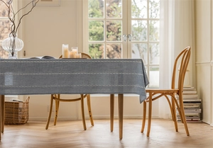 Detail shot of grey-blue linen textured tablecloth with white geometric lace on a wooden table