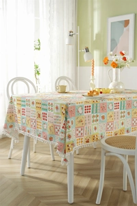 Detail of French cotton tablecloth with cherry prints and white pompom fringe trim