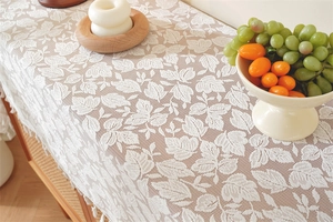 Close-up of French white lace table runner with leaf patterns and elegant tassel edges