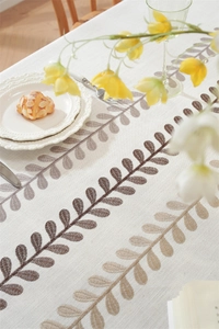 Detail of leaf embroidery on cream table cloth with elegant lace plate and cozy meal