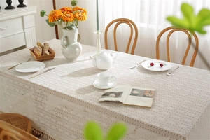 Close-up of beige lace tablecloth with geometric hollow patterns and fringe details