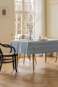 Detail of grey-blue jacquard tablecloth with white geometric patterns on a wooden table