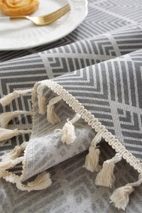 Close-up of bohemian geometric table runner with gray wave patterns and beige fringes