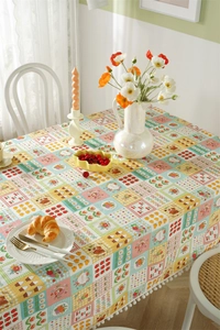 Close-up of French cotton tablecloth with patchwork floral prints and white pompom trim