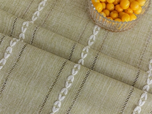 Close-up of sage green jacquard tablecloth with white leaf embroidery and hollow details