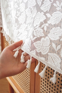 Detailed shot showing the white lace embroidery texture and tassel fringe of the table runner