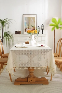 Close-up of beige lace tablecloth featuring geometric hollow patterns and fringe details