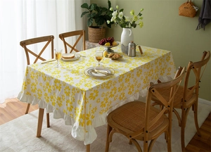 Detail of yellow daisy floral cotton tablecloth featuring elegant white ruffled edges