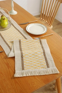 Detail of bohemian cotton linen table runner with yellow diamond weave and tassels