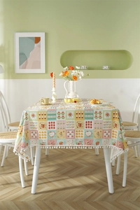 Detailed view of floral cotton tablecloth with strawberry prints and white pom-pom trim