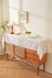 Close-up of beige French floral lace table runner with elegant white fringe tassels