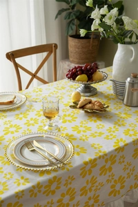 Close-up of yellow daisy print tablecloth featuring white ruffled edge detail