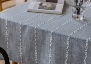 Macro detail of blue jacquard tablecloth featuring white vertical embroidered stripe patterns