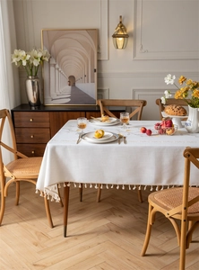 Detail of embroidered coffee leaf pattern and cream tassel fringe on cotton linen tablecloth