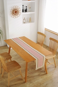 Close-up of woven linen table runner featuring red diamond patterns and fringe details
