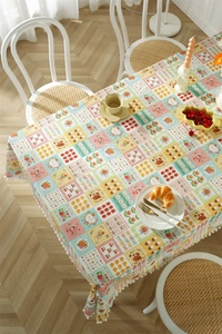 Detail of patchwork tablecloth with cartoon prints and white pom-pom lace trim edge