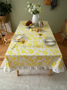 Detail of yellow daisy floral print on white cotton tablecloth with elegant ruffled edges