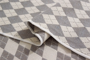 Dettaglio macro della tovaglia a rombi verde e beige con bordi rifiniti in bianco