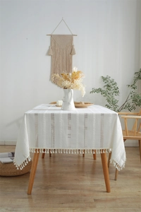 Detail of white polyester jacquard tablecloth featuring hollow fringe and tassel edges