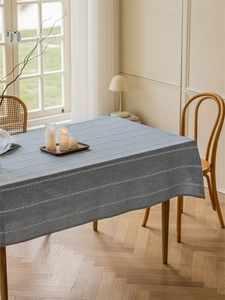 Detailed texture of grey-blue woven tablecloth with white cross-stitch embroidery