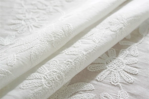 Close-up of white cotton floral embroidery with daisy patterns on frill tablecloth