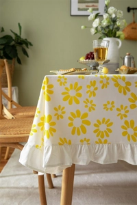 Detail of floral tablecloth showing yellow daisy patterns and elegant ruffled edges