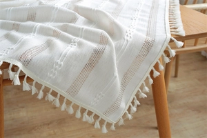 Detailed knit texture with hollow stripes and elegant white tassel fringe on wood table