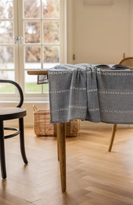 Detail of light blue tablecloth with white geometric embroidery and linen texture