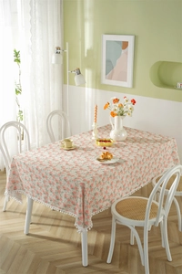 Detail of floral rectangular tablecloth with white pom-pom fringe and small pink flowers