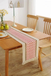 Detail of cotton linen table runner with red diamond pattern and woven fringe edges