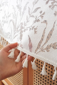 Macro view of white floral lace table runner with decorative fringe tassels on wood